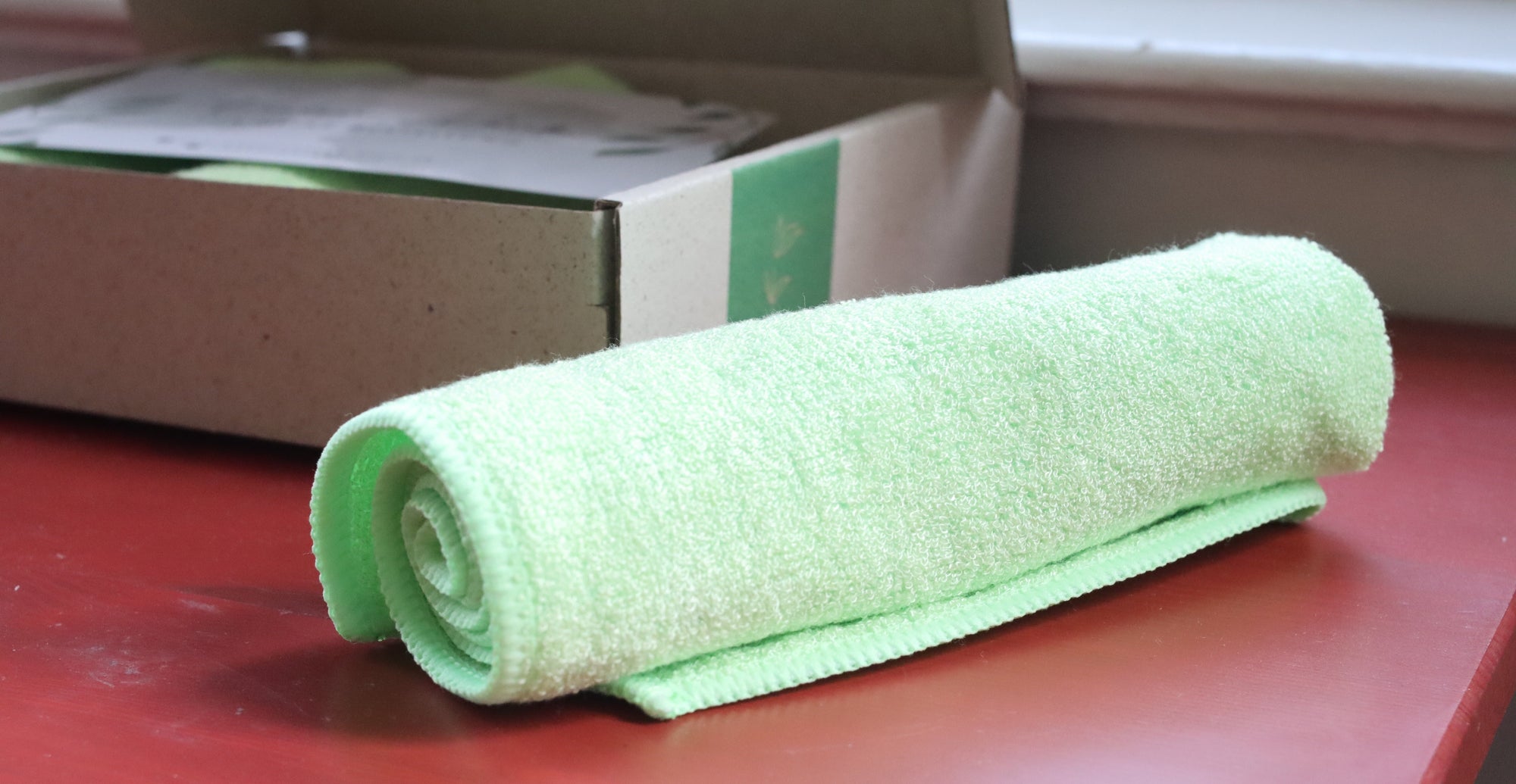 Das Grashüpfer Bambus Allzwecktuch liegt zusammengerollt neben der Verpackung.