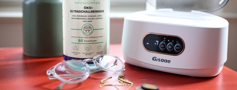 Brille liegt vor Ultraschallreiniger und Ultraschallbad.