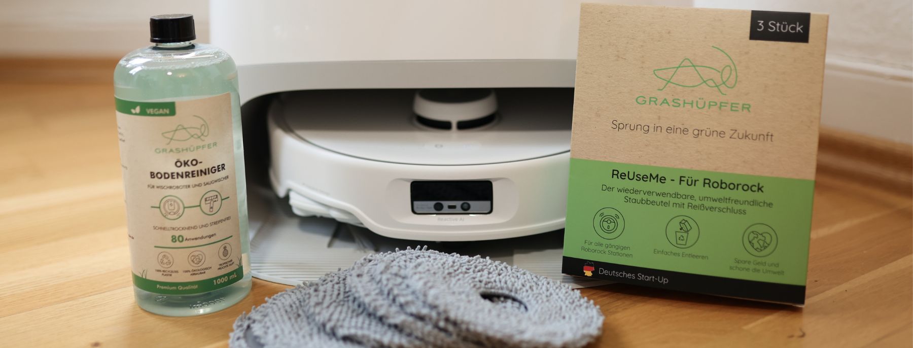 Verschiedene Roborock Ersatzteile und Alternativen wie Staubbeutel, Wischpads und Reinigungsmittel von Grashüpfer sind neben einem Roborock Qrevo Modell zu sehen und es stellt sich die Frage, ob sie genauso gut oder gar besser sind und ob sie sich lohnen.