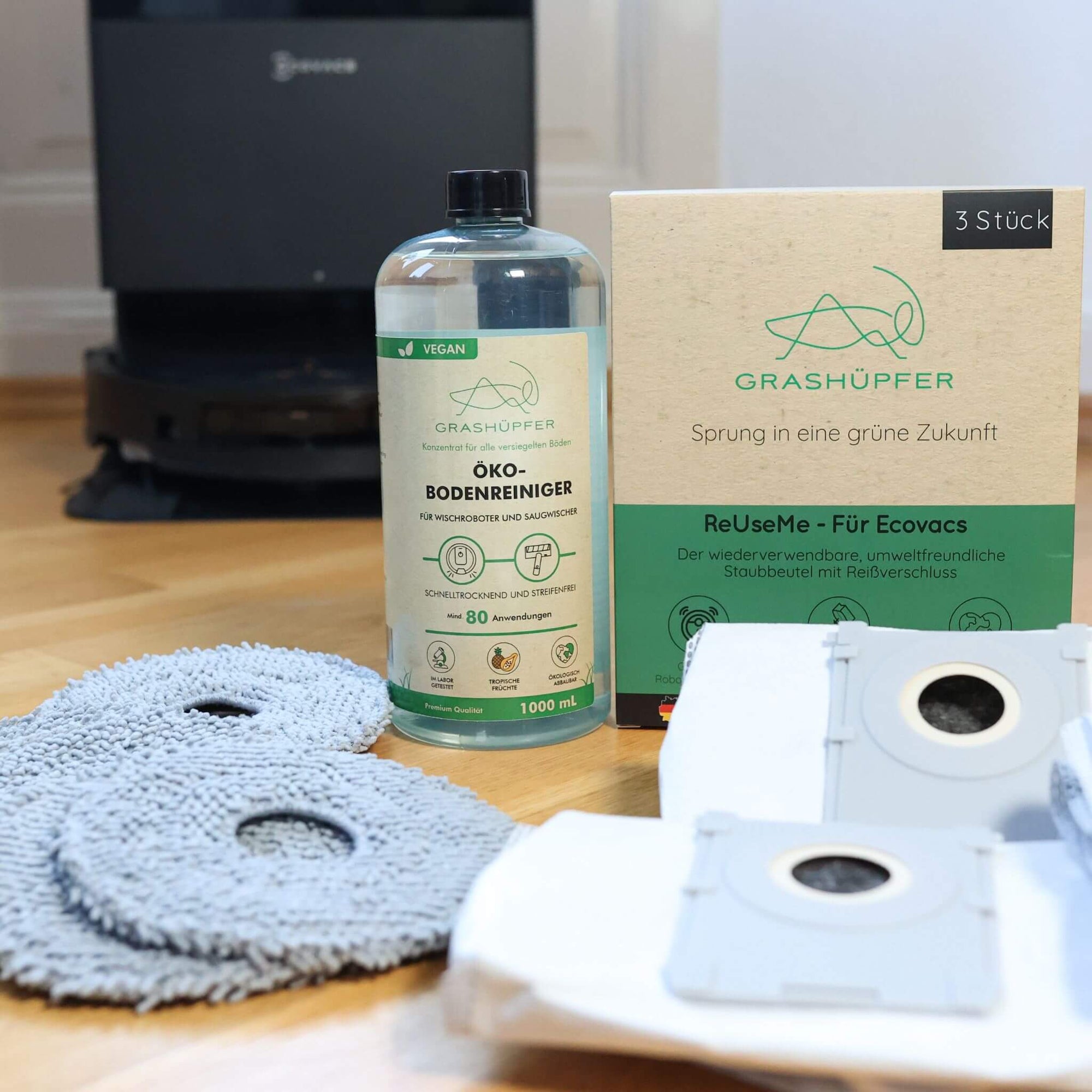 Das ECOVACS DEEBOT Sorglospaket von Grashüpfer ist in einzelteilen zu sehen, es gibt 6 Wischpads, ein Öko-Bodenreiniger für Wischroboter und 3 ReUseMe Staubbeutel für ECOVACS Saugroboter mit Reißverschluss.