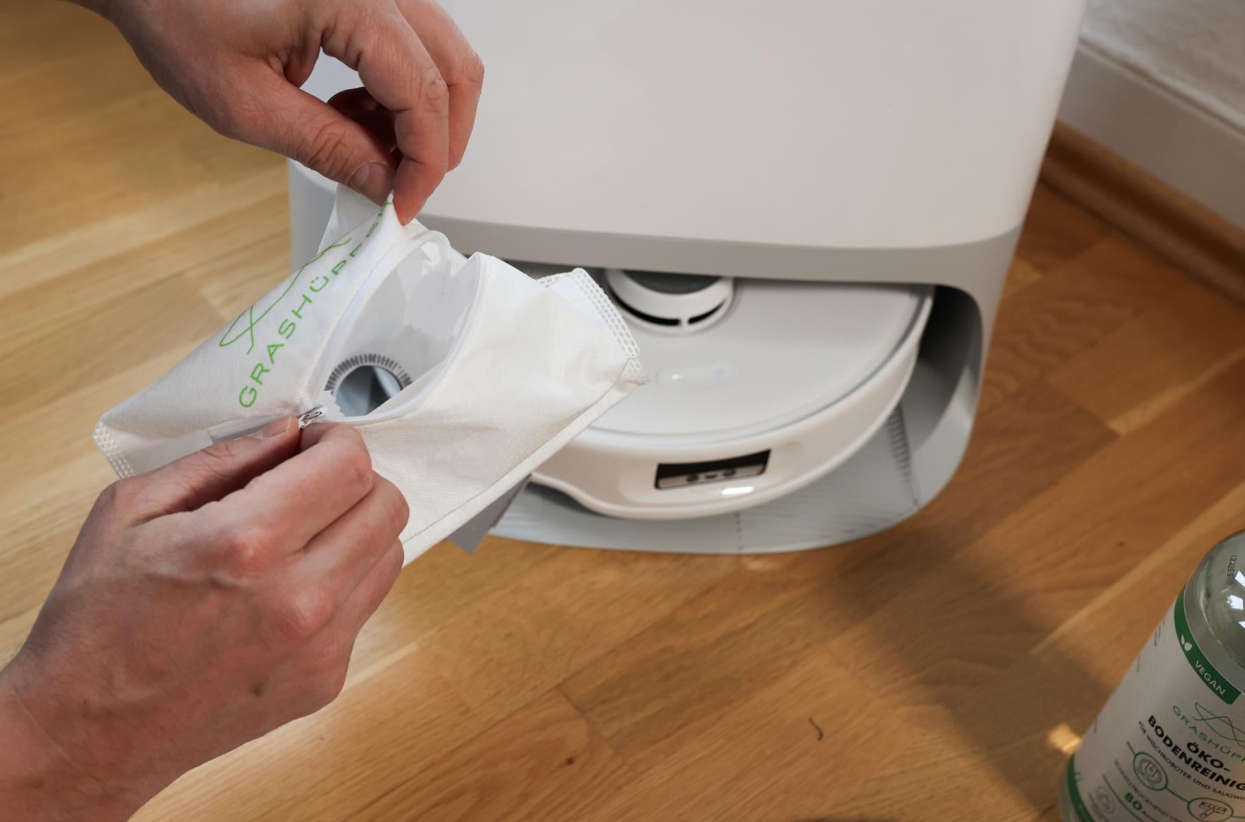 Ein Staubbeutel, Teil des Grashüpfer Sorglospaket für Roborock Saugroboter, wird per Reißverschluss geöffnet, um die einfache Entleerung zu zeigen.