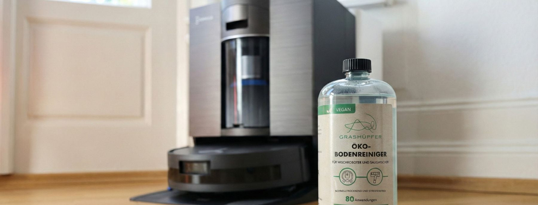 Eine ECOVACS DEEBOT Reinigungsmittel Alternative von Grashüpfer steht vor dem ECOVACS DEEBOT X11 OmniCyclone samt OMNI-Station.