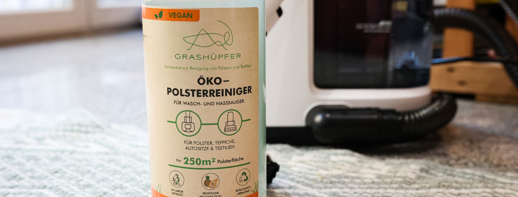  Polsterreiniger steht neben Staubsaugerbuerste auf dem Sofa.