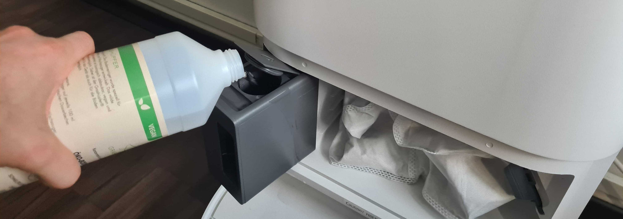 Der Grashüpfer Öko-Bodenreiniger für Wischroboter und Saugwischer wird in die Station des Dreame Saug- und Wischroboters geschüttet.