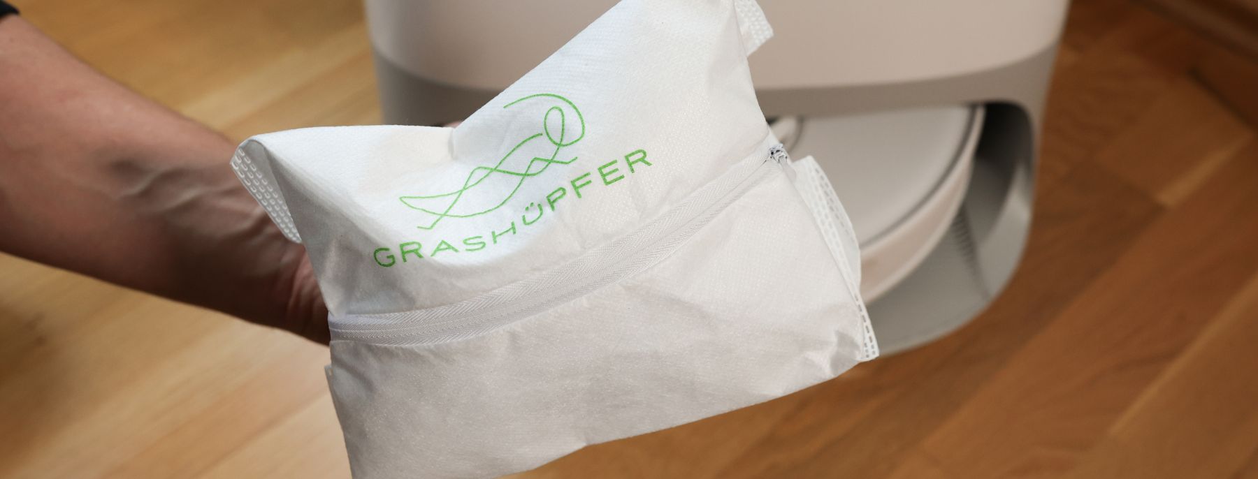 Grashuepfer Staubbeutel wird in die Roborock Station gelegt.