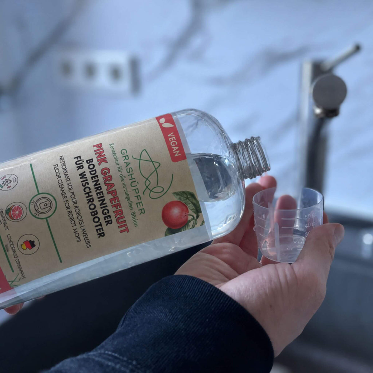 GRASHÜPFER Bodenreiniger Pink Grapefruit wird zur Dosierung in einen Messbecher gefüllt.