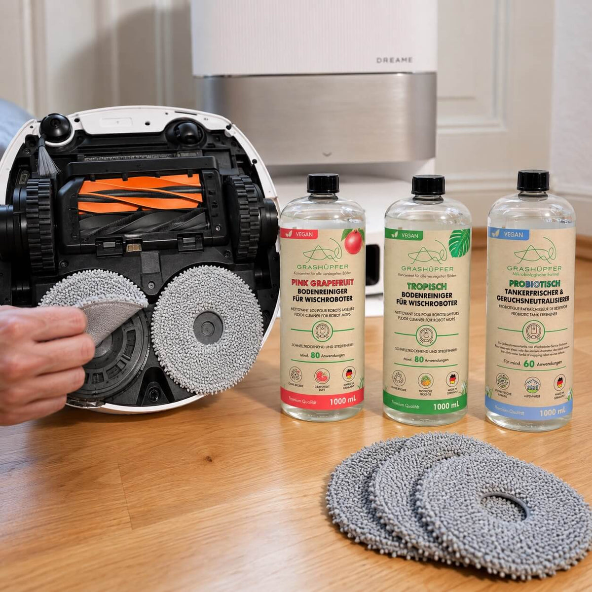 Dreame Saug-Wischroboter beim Wischpad-Wechsel mit Grashüpfer Bodenreiniger, Tankerfrischer und zusätzlichen Wischpads.