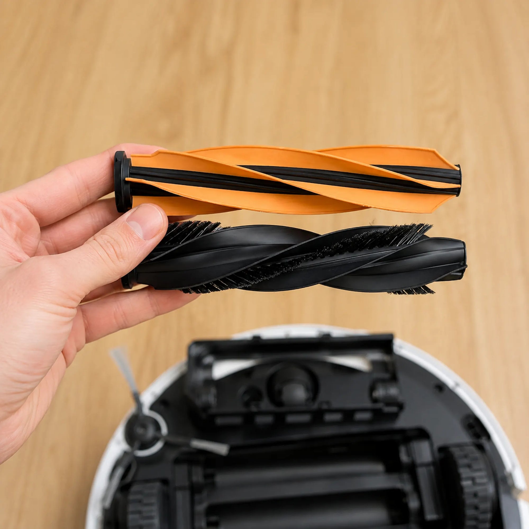 GRASHÜPFER Ersatz-Hauptbürsten für MOVA Saugroboter, orange und schwarze Bürstenrolle beim Wechseln vor dem geöffneten Roboter.