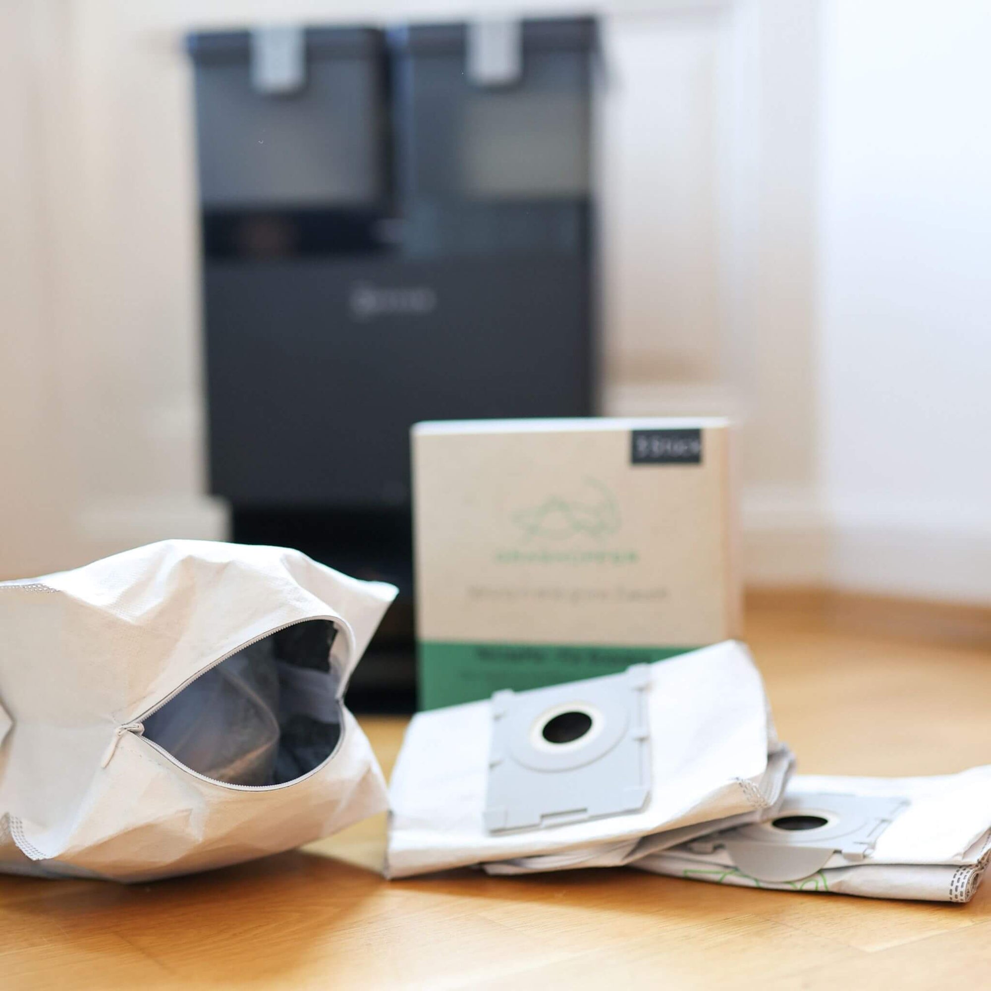 Die 3 Grashüpfer ReUseMe Staubbeutel für ECOVAS DEEBOT Saug- und Wischroboter liegen vor der Verpackung und einer der Beutel ist per Reißverschluss geöffnet.