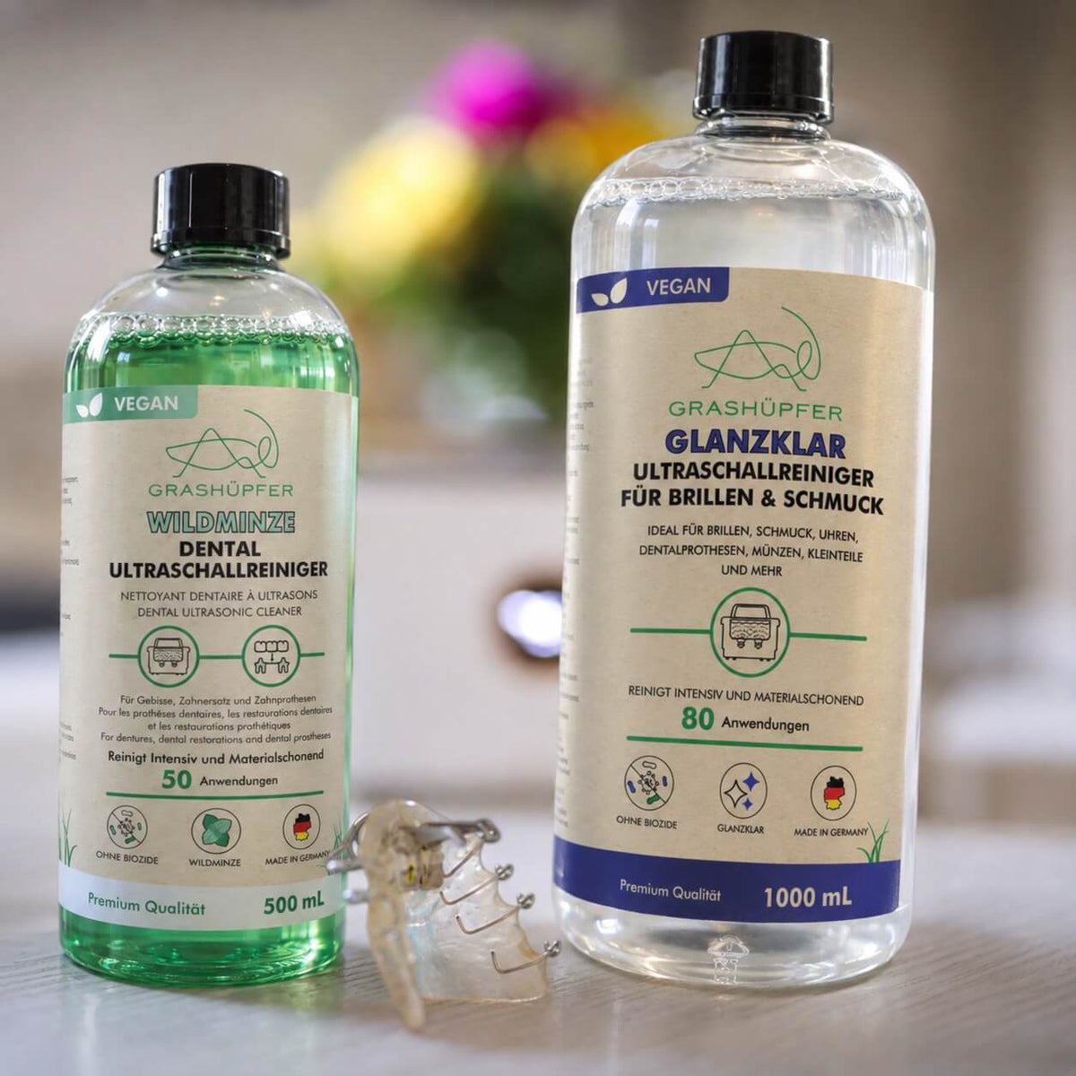 GRASHÜPFER Ultraschallreiniger Duo mit Dental Wildminze 500 ml und Glanzklar 1000 ml neben Zahnersatz im Wohnambiente.